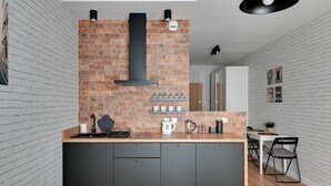 A modern kitchen with a brick backsplash, black cabinets, and a wooden countertop. - Grand Apartments - Bastion Wałowa (Gdansk)