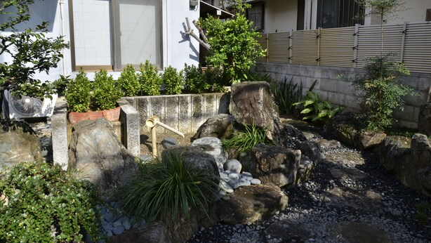 A garden with rocks, plants, and a wooden fence. - Ho-ma ya (Ishigaki)