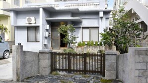 A modern two-story house with a stone wall and a black gate. - Ho-ma ya (Ishigaki)