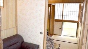 A traditional Japanese room with tatami flooring, a low wooden table, and a sliding door leading to a balcony. - Ho-ma ya (Ishigaki)