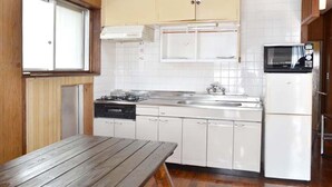 A compact kitchen with white cabinets, a stove, a sink, and a microwave. - Ho-ma ya (Ishigaki)