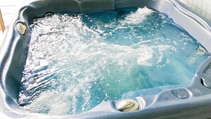 Un bain à remous équipé de jets d’eau, d’un panneau de commande et d’un mur carrelé en arrière-plan.