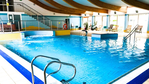 Une piscine intérieure dotée d’un plongeoir, d’échelons et de chaises longues.