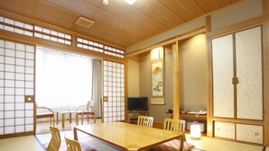 Una stanza tradizionale giapponese con pavimenti in tatami, un tavolino in legno e pannelli scorrevoli shoji.