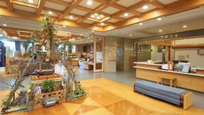 Una hall d'albergo con reception, una zona reception in legno e un'elegante composizione floreale.