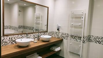 A bathroom with two sinks, a mirror, and a towel rack.