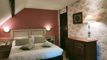 Un dormitorio con cama, mesitas de noche, cómoda, lámpara de pared y un cuadro enmarcado.