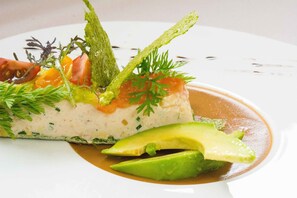 A dish with avocado, salmon, and greens on a white plate. - La Chaumière (Aubigny-sur-Nere)