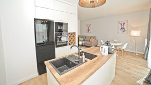 A modern kitchen with a central island, built-in appliances, and a dining area with a table and chairs. - Grand Apartments - Modern Old Town (Gdansk)