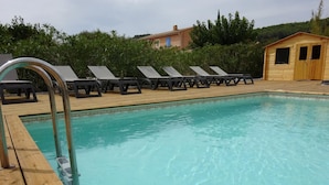 Una piscina con sillas de descanso y una terraza de madera.