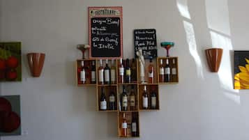 Un présentoir à bouteilles de vin, avec des bouteilles et deux panneaux noirs indiquant l’origine des vins.