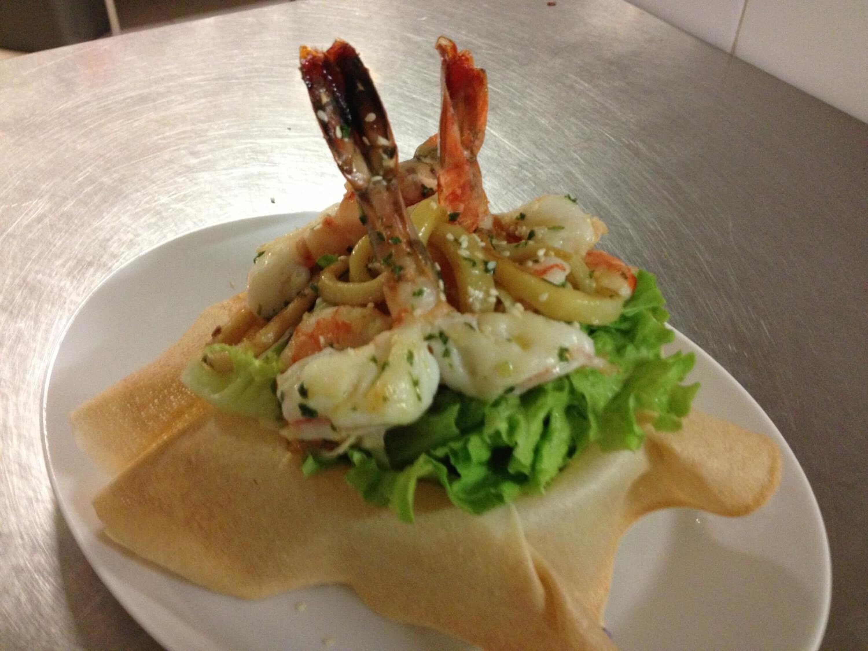 A plate of seafood salad with lettuce and a lemon wedge.