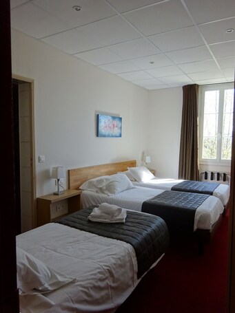 A hotel room with three beds, a wooden headboard, a painting on the wall, and a window with curtains.