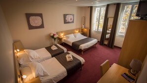 Habitación de hotel con dos camas, un escritorio, una silla y un televisor.