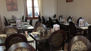 Un restaurante con mesas y sillas de madera oscura, cada juego con copas de vino y menús.
