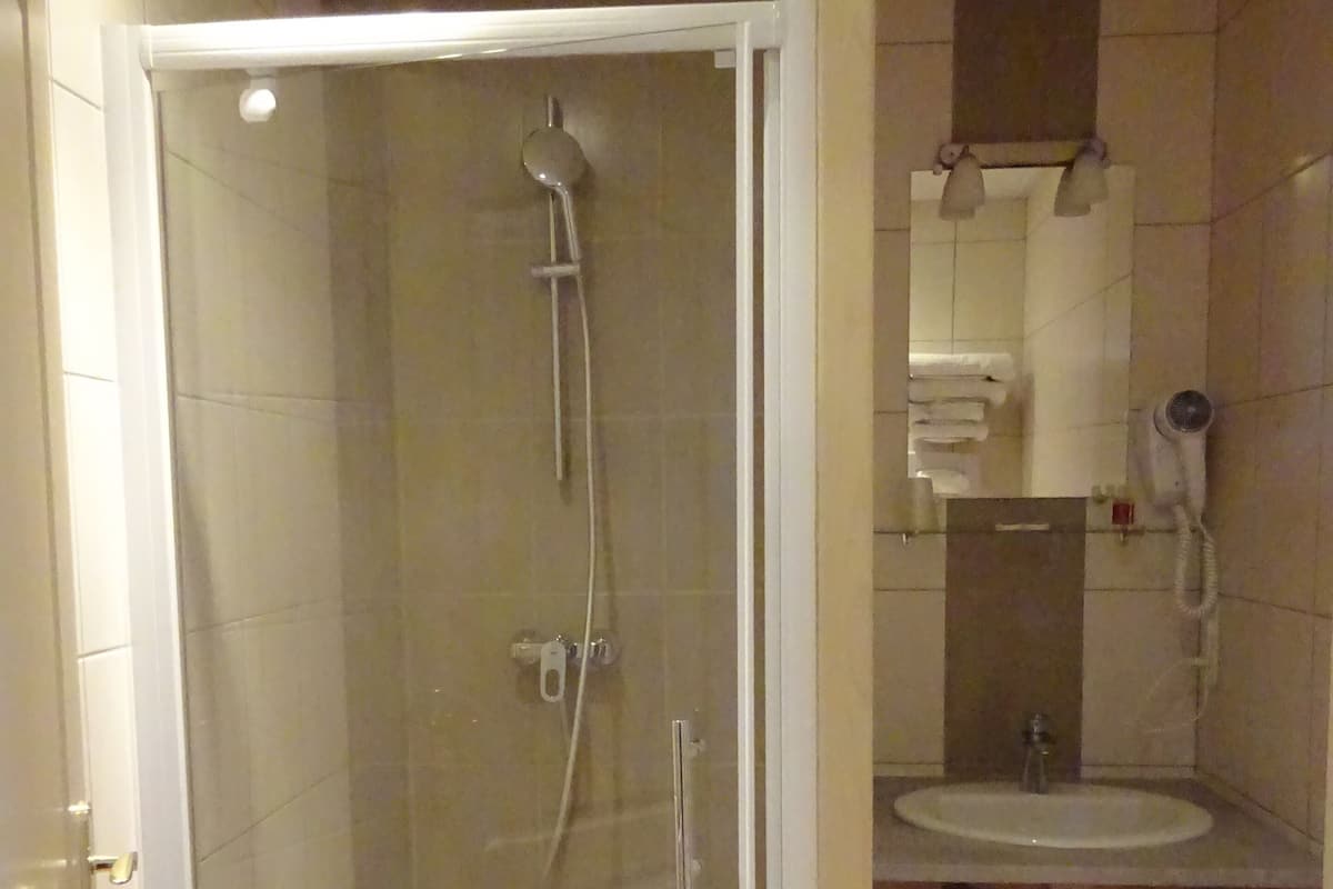 A bathroom with a glass-enclosed shower, a sink, and a toilet.