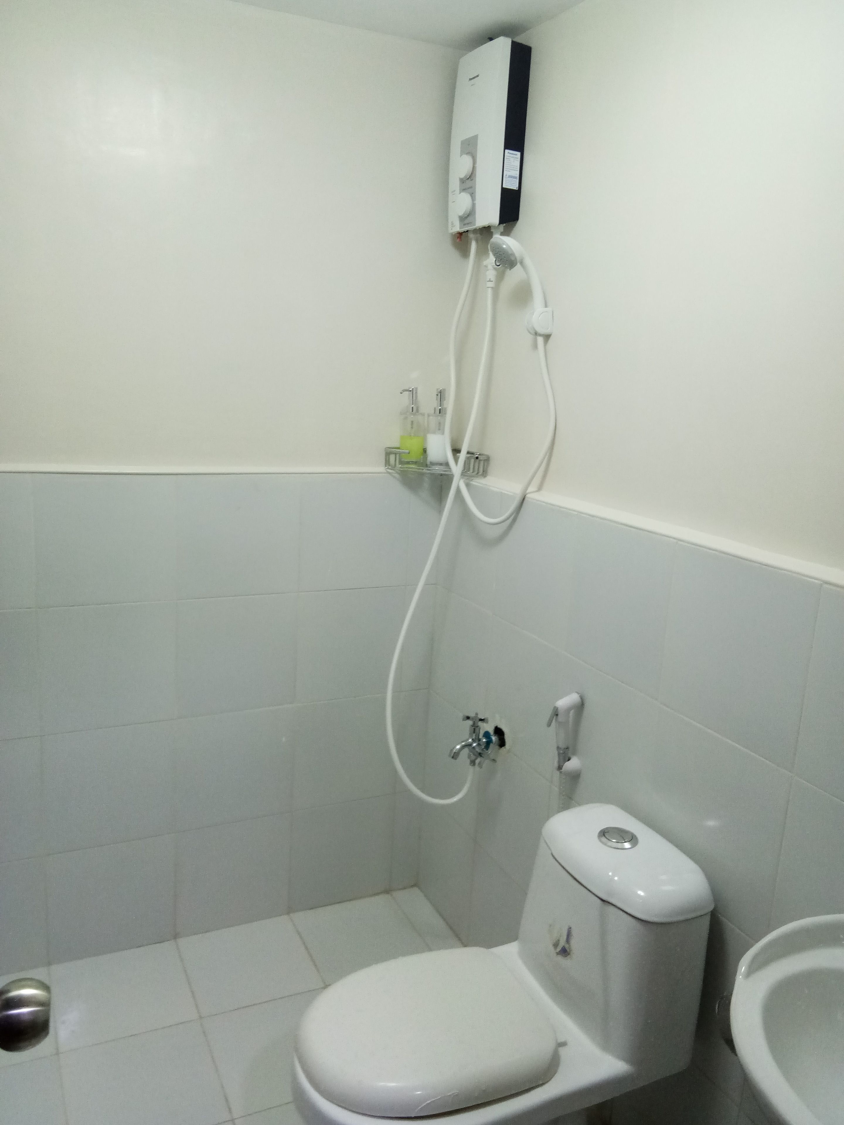 A small, white bathroom with a toilet, bidet, and a water heater mounted on the wall.