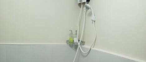 A small, white bathroom with a toilet, bidet, and a water heater mounted on the wall.