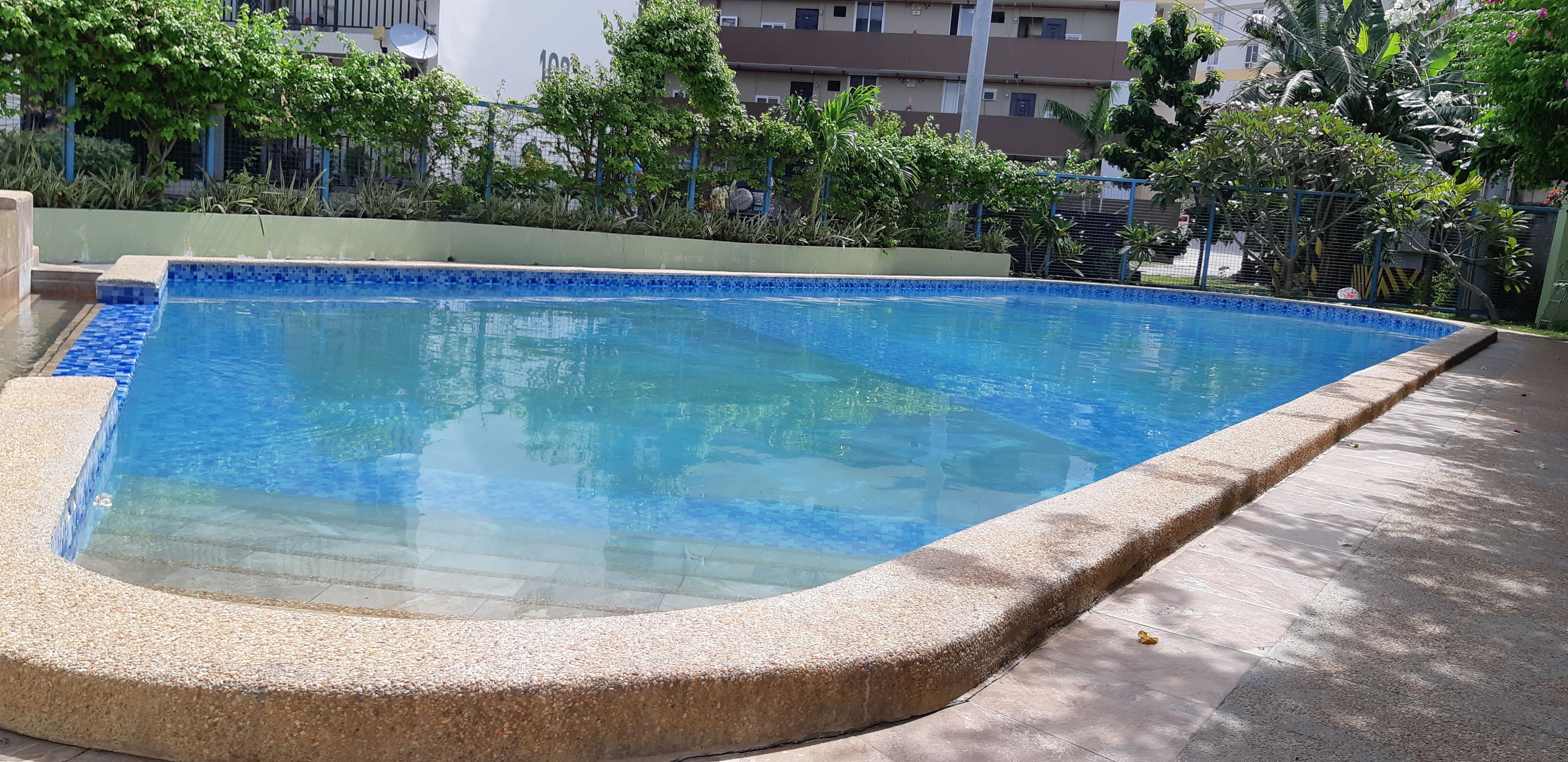 A rectangular pool with a blue-tiled edge, surrounded by a pebble border.