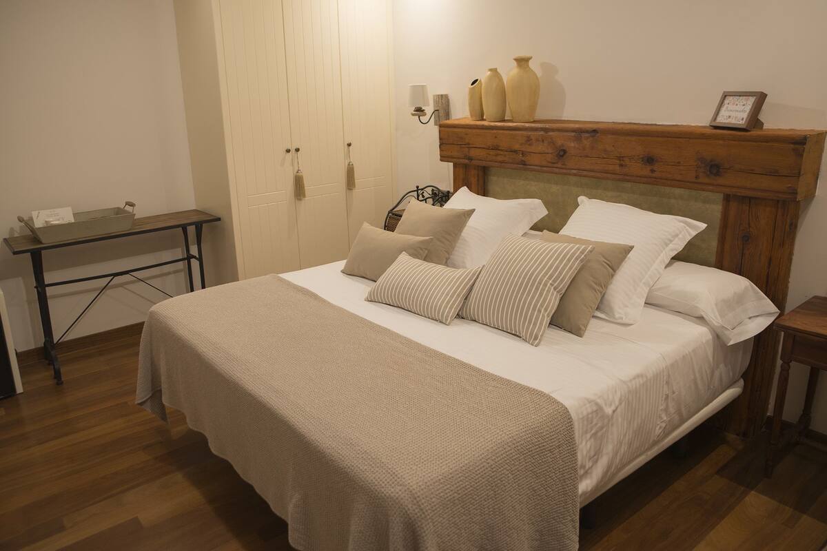 Una cama bien hecha con cabecera de madera, una mesita de noche y una lámpara de noche.