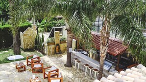 Un espace extérieur aménagé en terrasse, avec un sol en pierre, des meubles en bois et un barbecue.