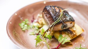 Une assiette contenant un morceau de viande, des légumes et une sauce.