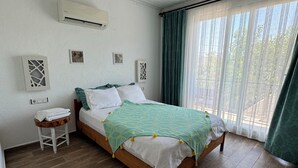 Un dormitorio con cama de madera, mesita de noche, aire acondicionado instalado en la pared y ventana con cortinas.