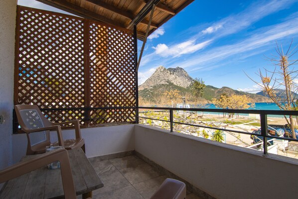 A balcony with a view of a mountain, a wooden table, and two chairs.