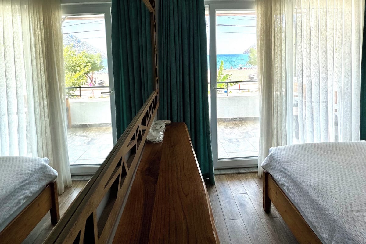 Una habitación con dos camas, un banco de madera y vistas al mar a través de amplios ventanales.