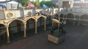 A courtyard with a statue of a knight on horseback, arches, and a flag. - Camelot (Villarrobledo)