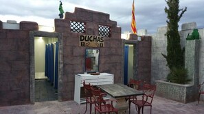 Un bâtiment à thème, avec une enseigne indiquant « DUCHAS » et un miroir au-dessus d’une table en bois, agrémentée de chaises rouges.