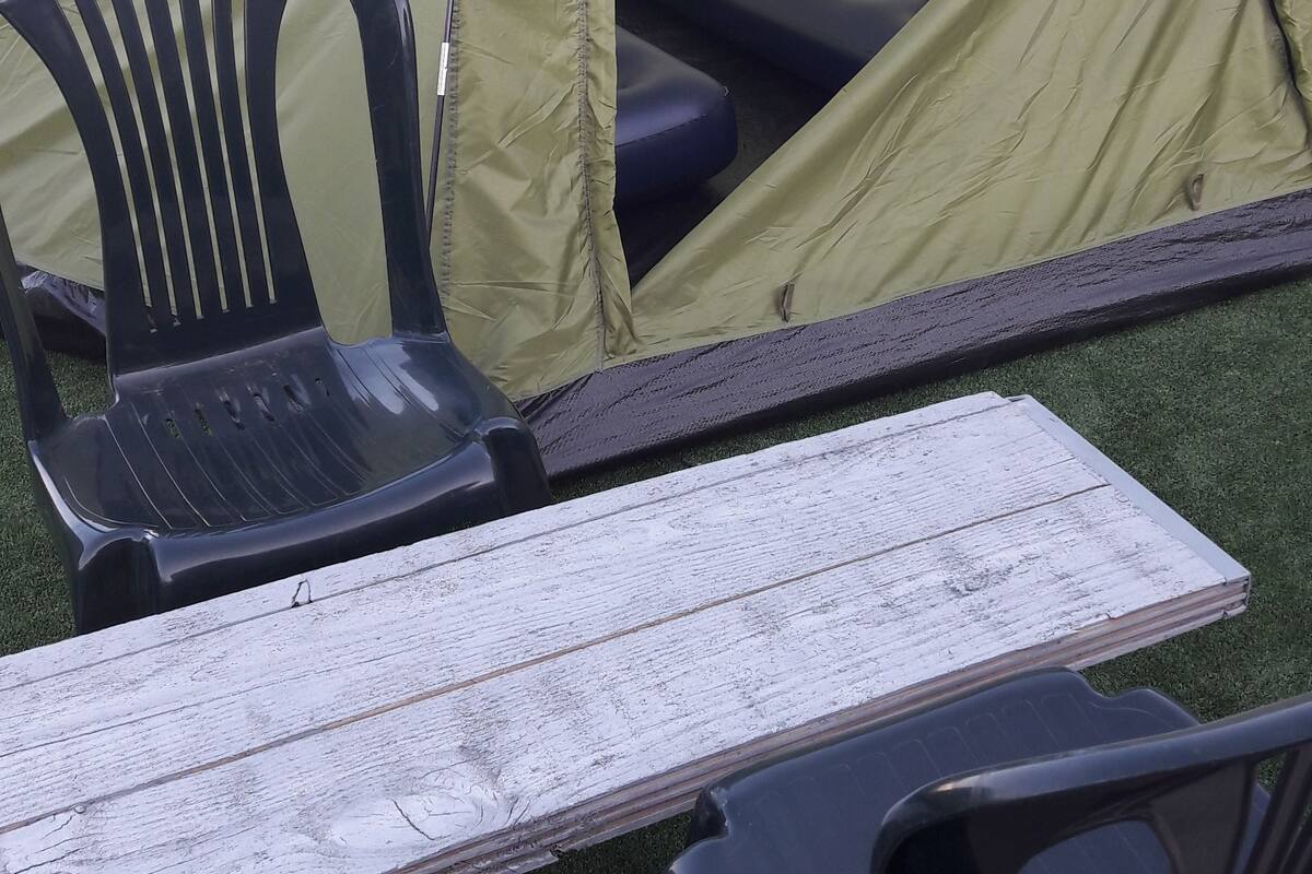 A camping setup with a tent, a table, and two chairs.