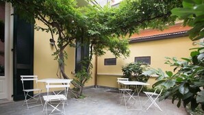 A courtyard with outdoor seating, a yellow wall, and a tree. - B&B La Foresteria (Milan)