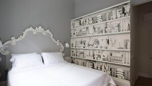 A bedroom with a large bed, a decorative headboard, and a wall of white sculptures. - B&B La Foresteria (Milan)