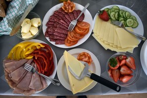 A table with various food items including sliced ham, cheese, tomatoes, cucumbers, and strawberries. - Håveruds Hotell (Håverud)