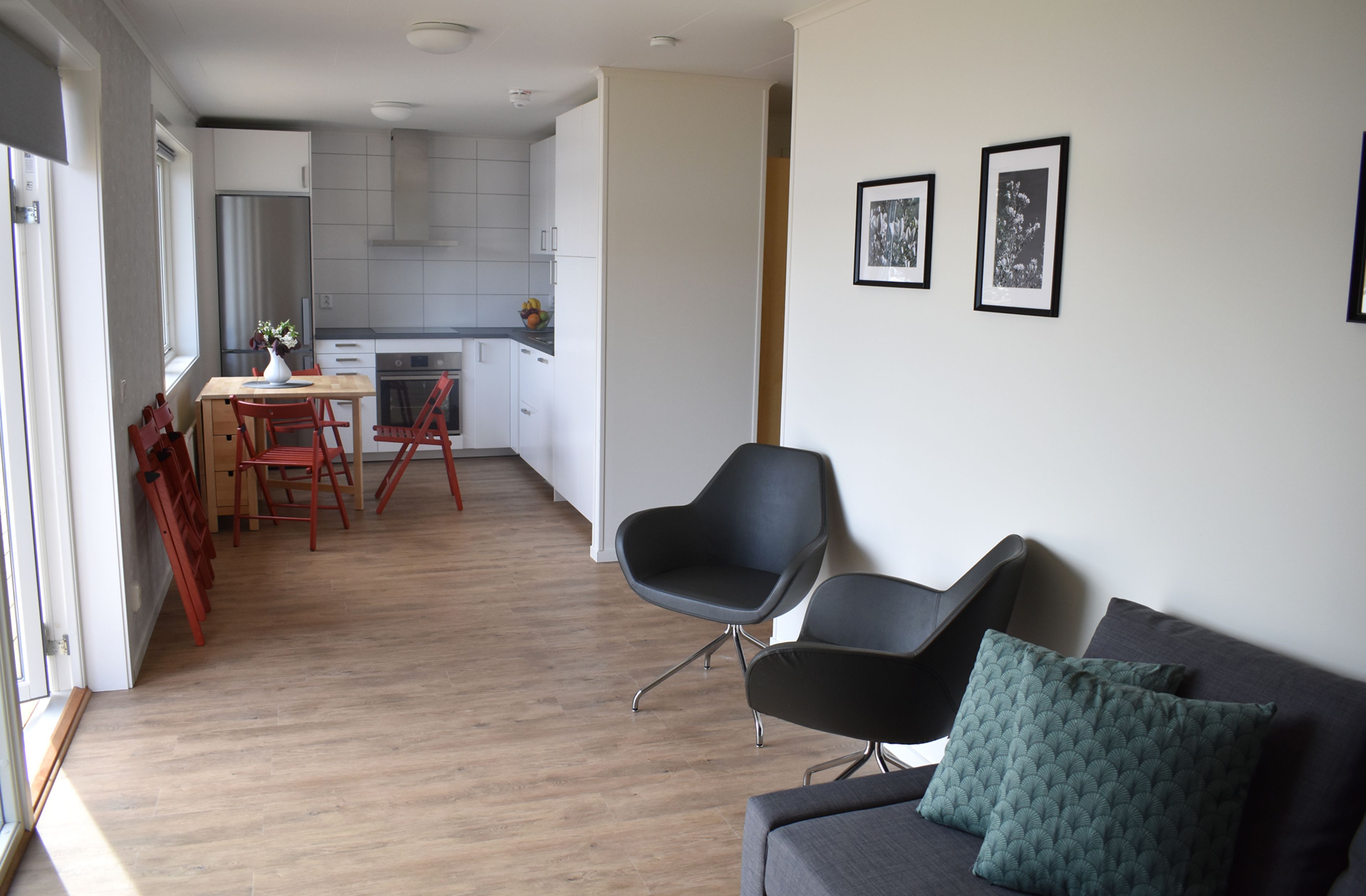 Un espacio de estar moderno con un sofá, una mesa de comedor con sillas y una cocina al fondo.
