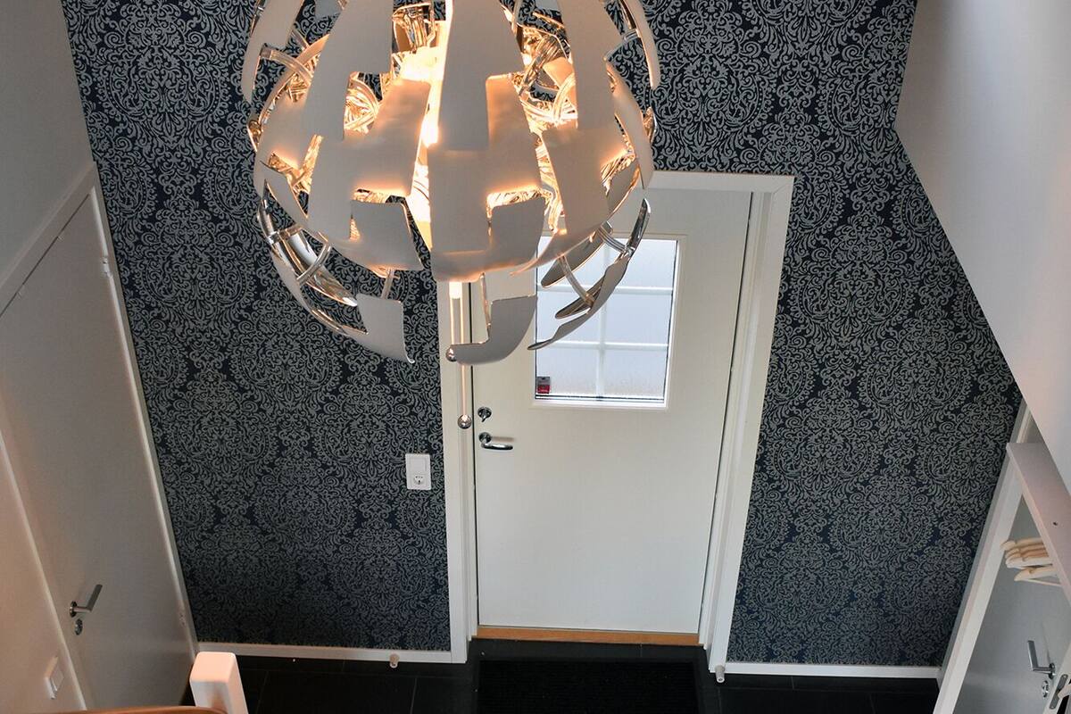 Um interior moderno com uma escada em espiral, uma porta branca e uma parede estampada.