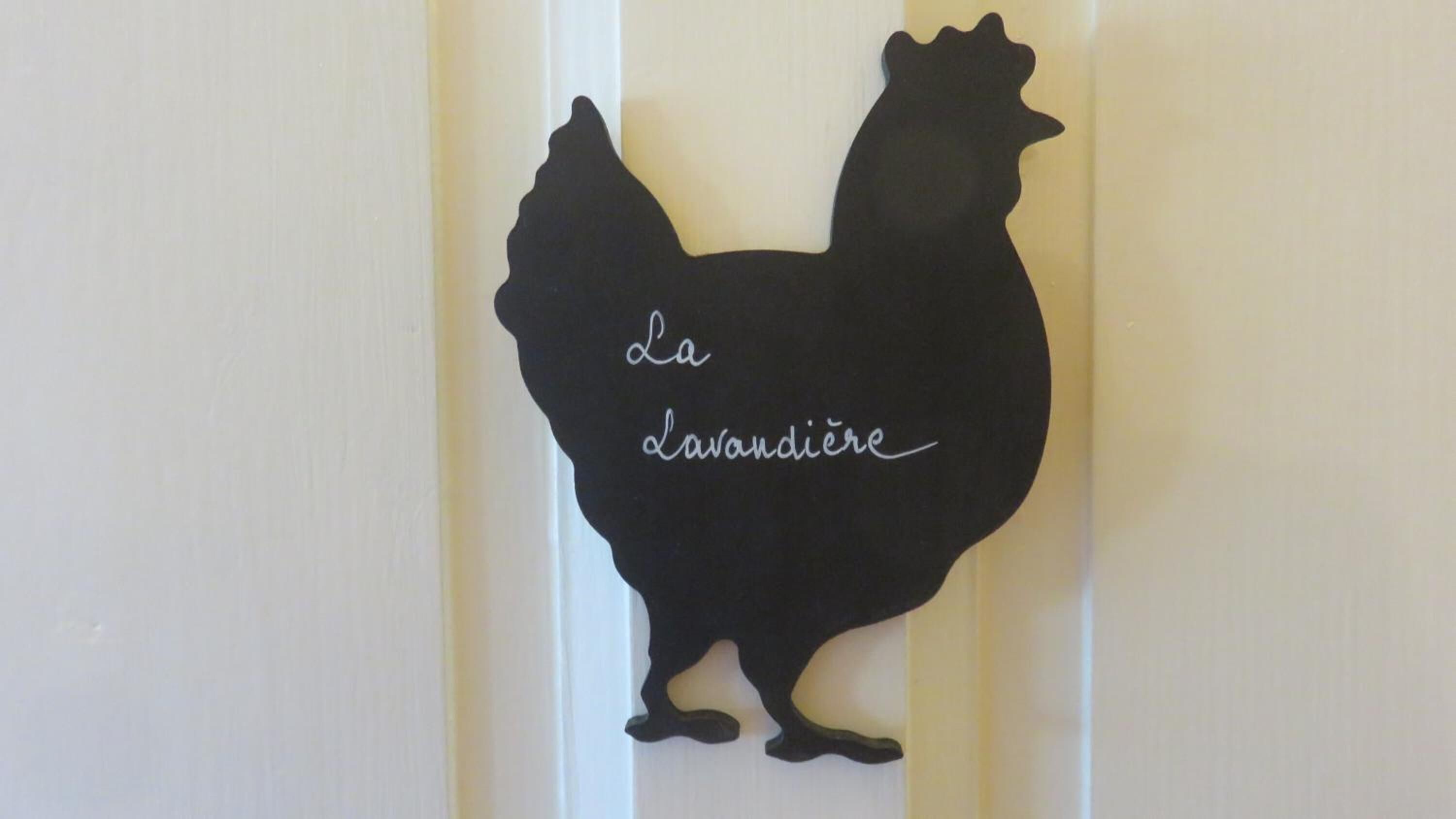 Zwarte silhouet van een haan met de tekst 'la lavandière' op een witte achtergrond.
