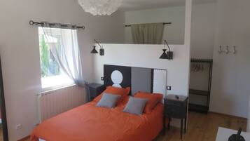 Un dormitorio con una cama, mesitas de noche, una ventana con cortinas, una lámpara en el techo y un estante en la pared.