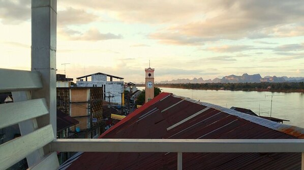 Vista de un río con montañas al fondo, una torre del reloj y edificios a lo largo de la orilla.