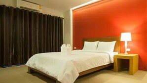 Habitación de hotel con cama, mesita de noche y una lámpara, y cortina.