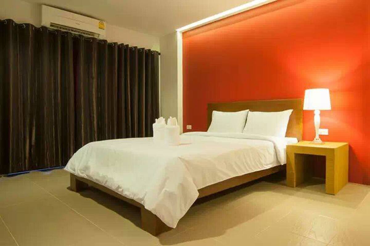 A hotel room with a bed, a nightstand with a lamp, and a curtain.