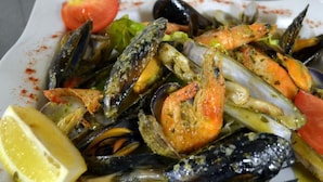 A plate of cooked seafood including mussels and shrimp, garnished with lemon and tomato slices. - L'Hôtel du Port (Port-la-Nouvelle)