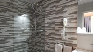 A modern bathroom with a glass shower enclosure, a white toilet, a sink with a mirror, and a towel rack. - L'Hôtel du Port (Port-la-Nouvelle)