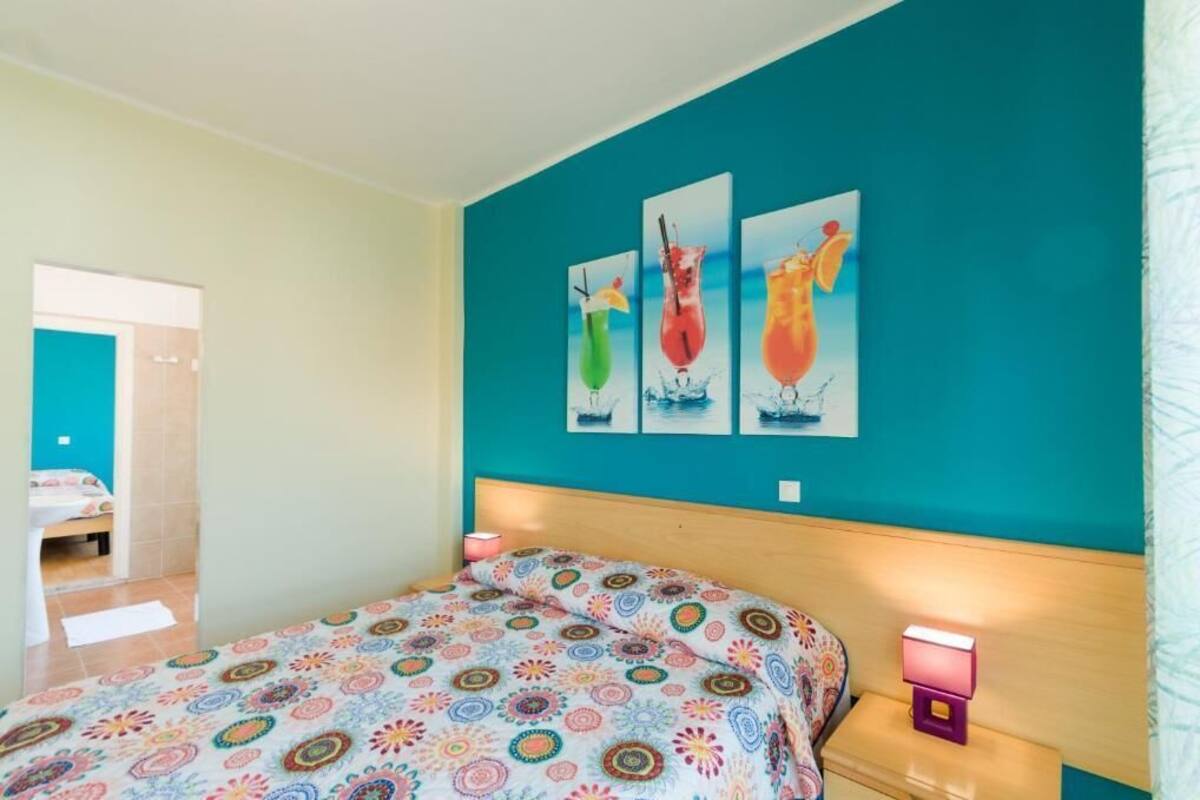 Une chambre à coucher avec un lit, une table de chevet et un mur orné de trois tableaux encadrés.