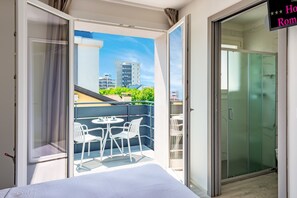 Een hotelkamer met balkon, een bed, een tafel met stoelen en een schuifdeur.