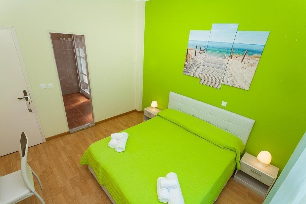 Een kamer met een bed, een nachtkastje, een stoel en een deur naar een badkamer.