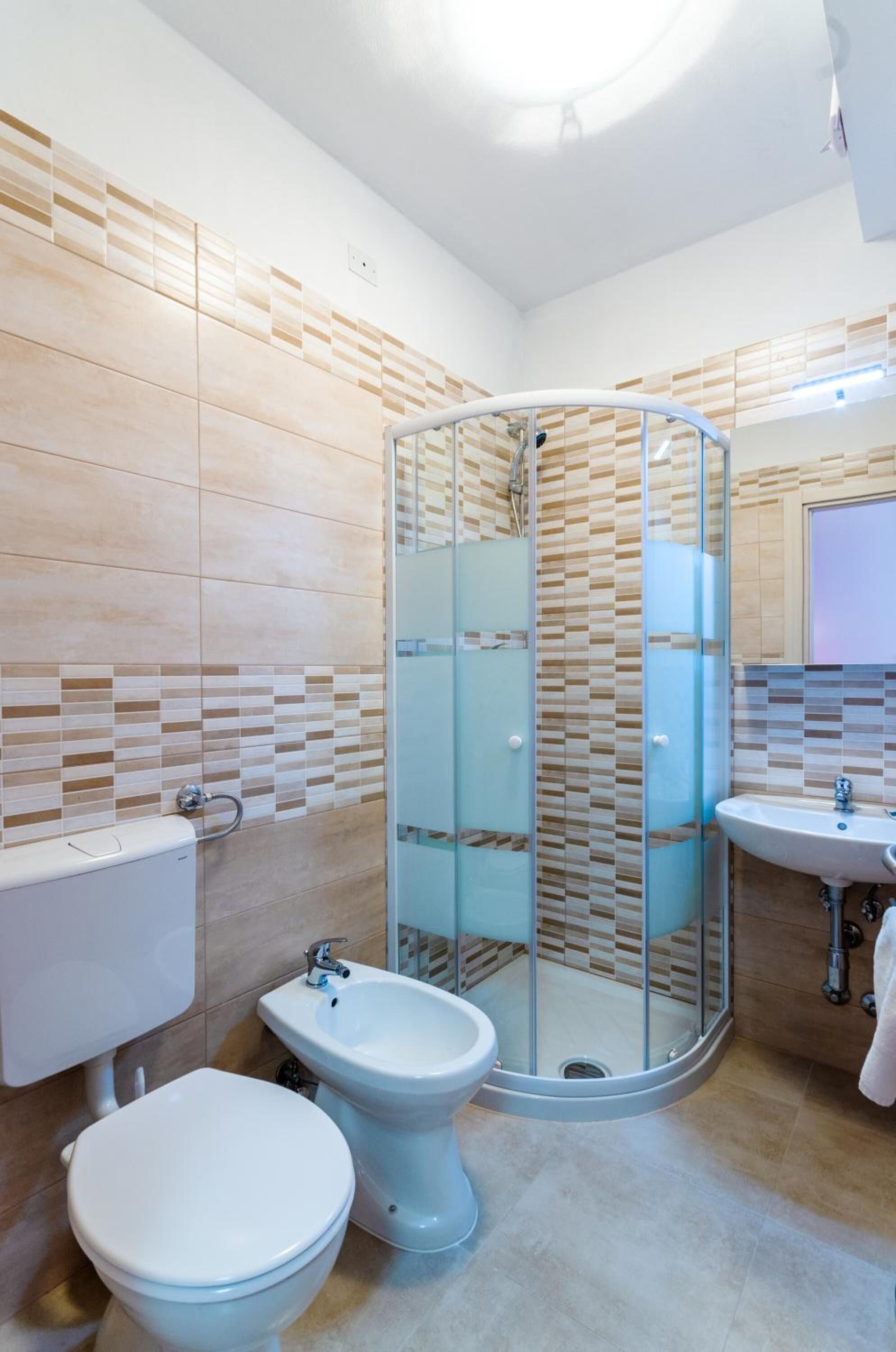 Ein modernes Badezimmer mit einer Duschkabine, einem Bidet, einer Toilette und einem Waschbecken.