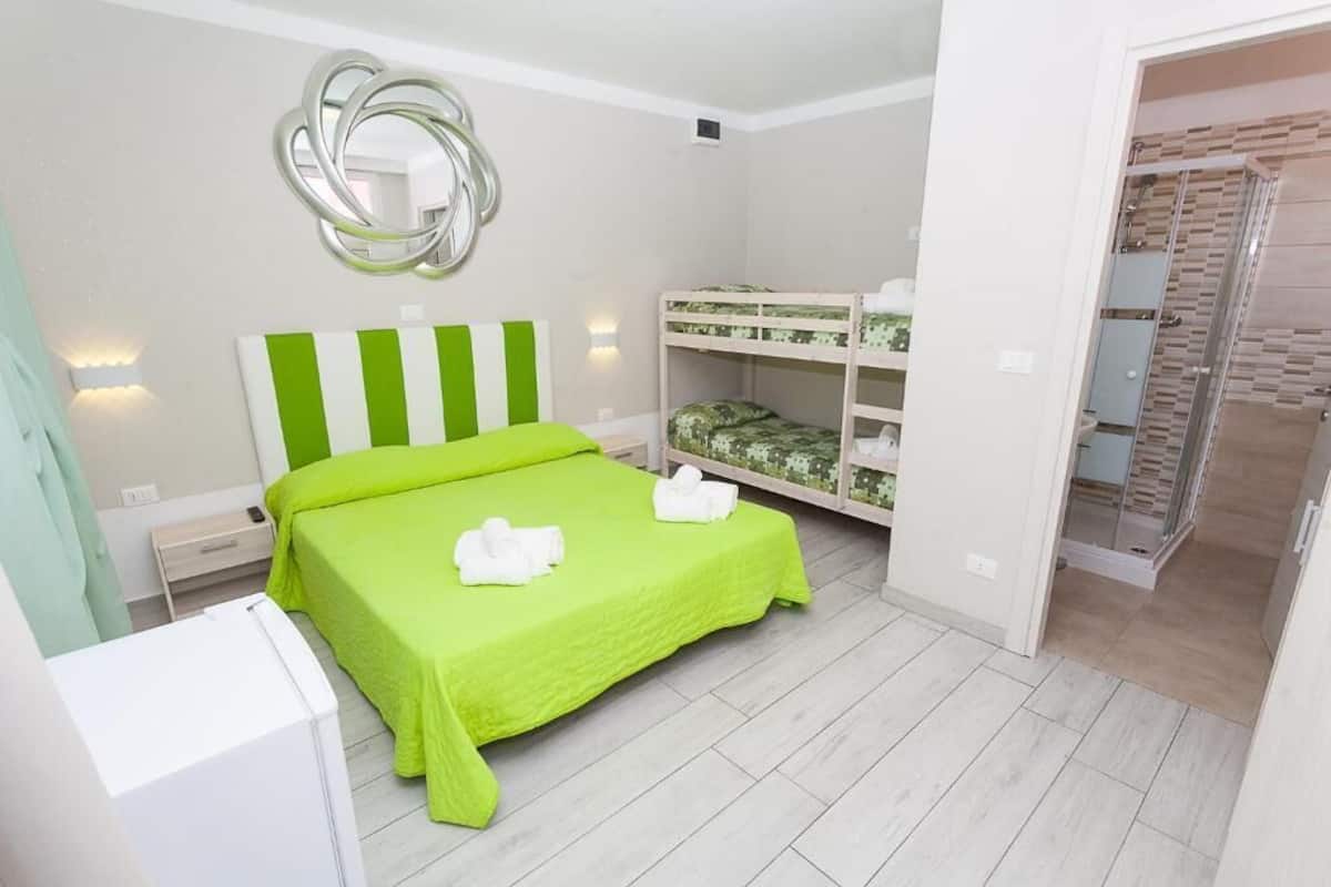 Une chambre avec un lit vert, des lits superposés, un miroir et un dressing.