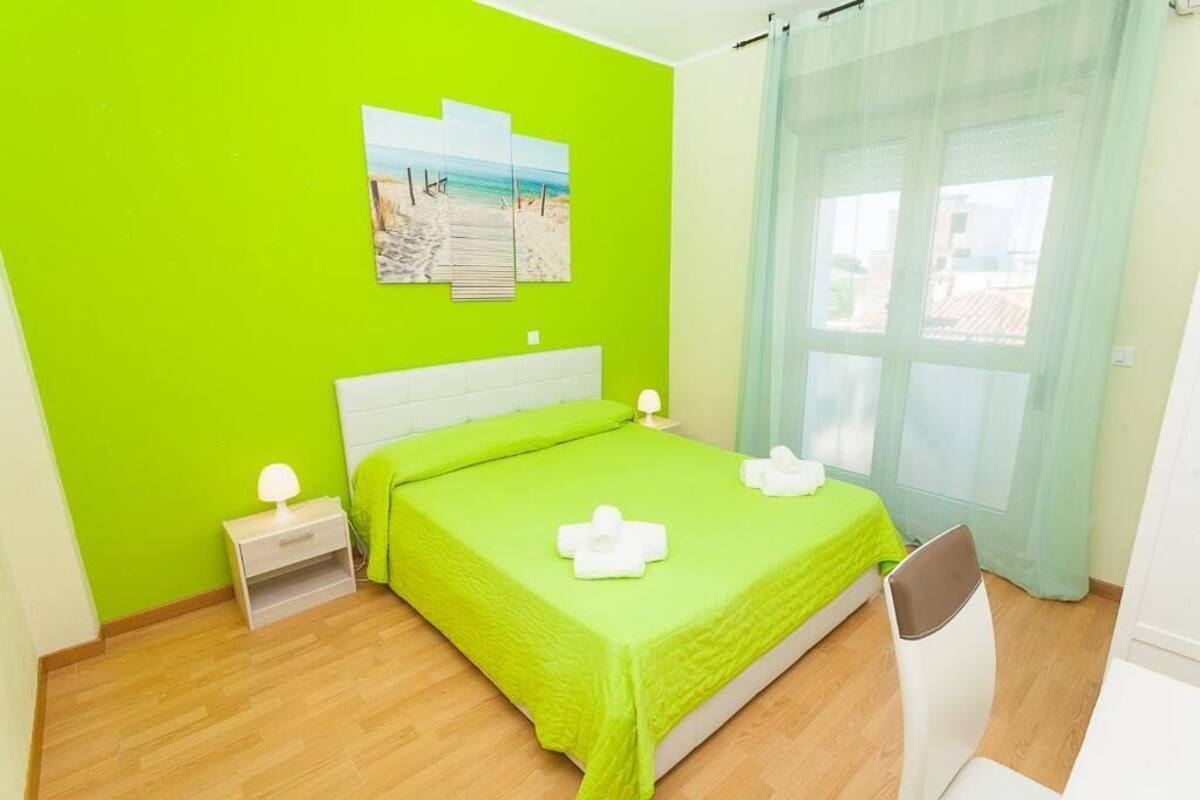 Une chambre avec un lit, une table de chevet, une chaise, une fenêtre avec des rideaux et une décoration murale sur le thème de la plage.